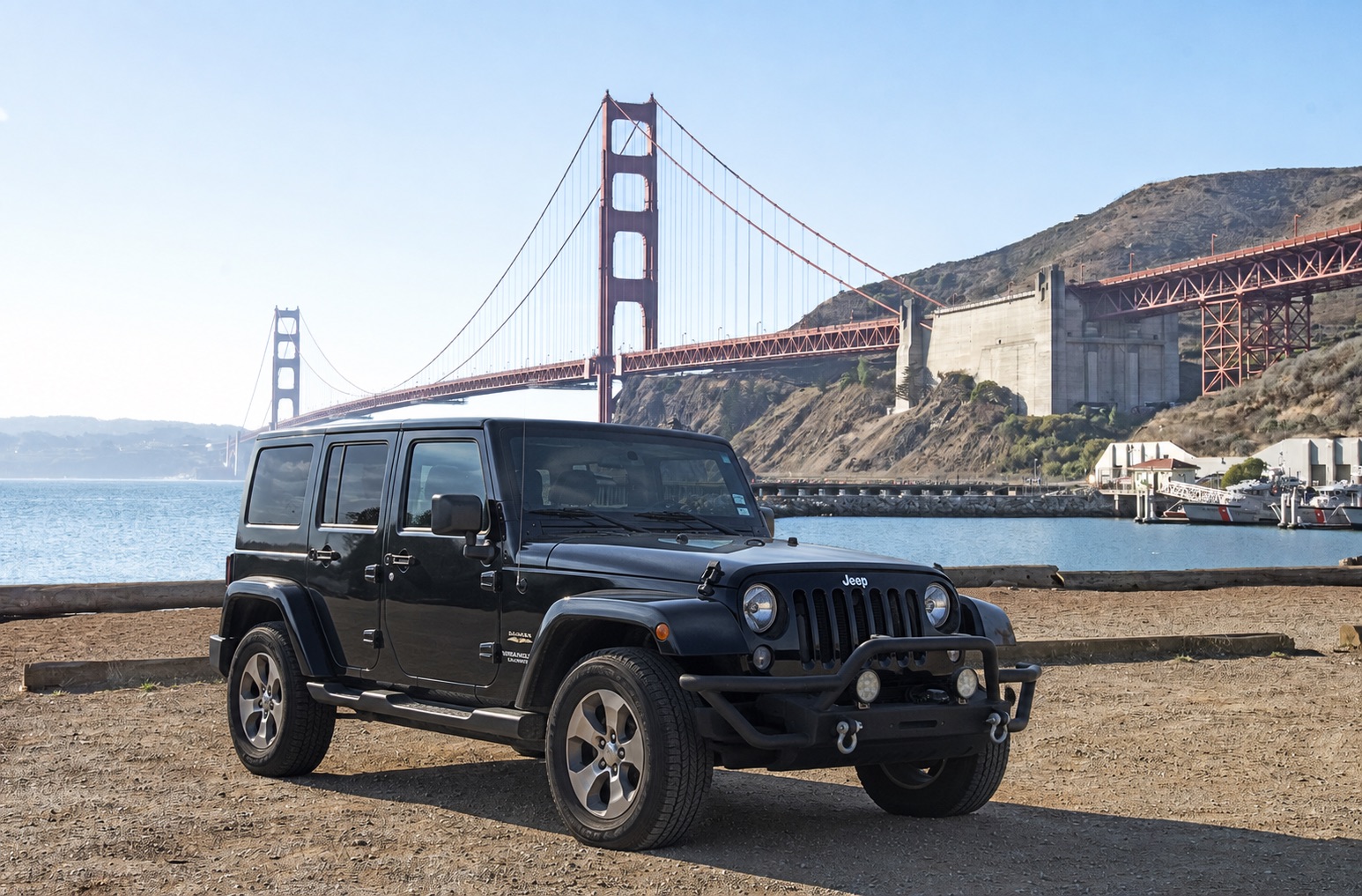The black 2015 Jeep Wrangler Unlimited Sahara parked in front of the Golden Gate Bridge